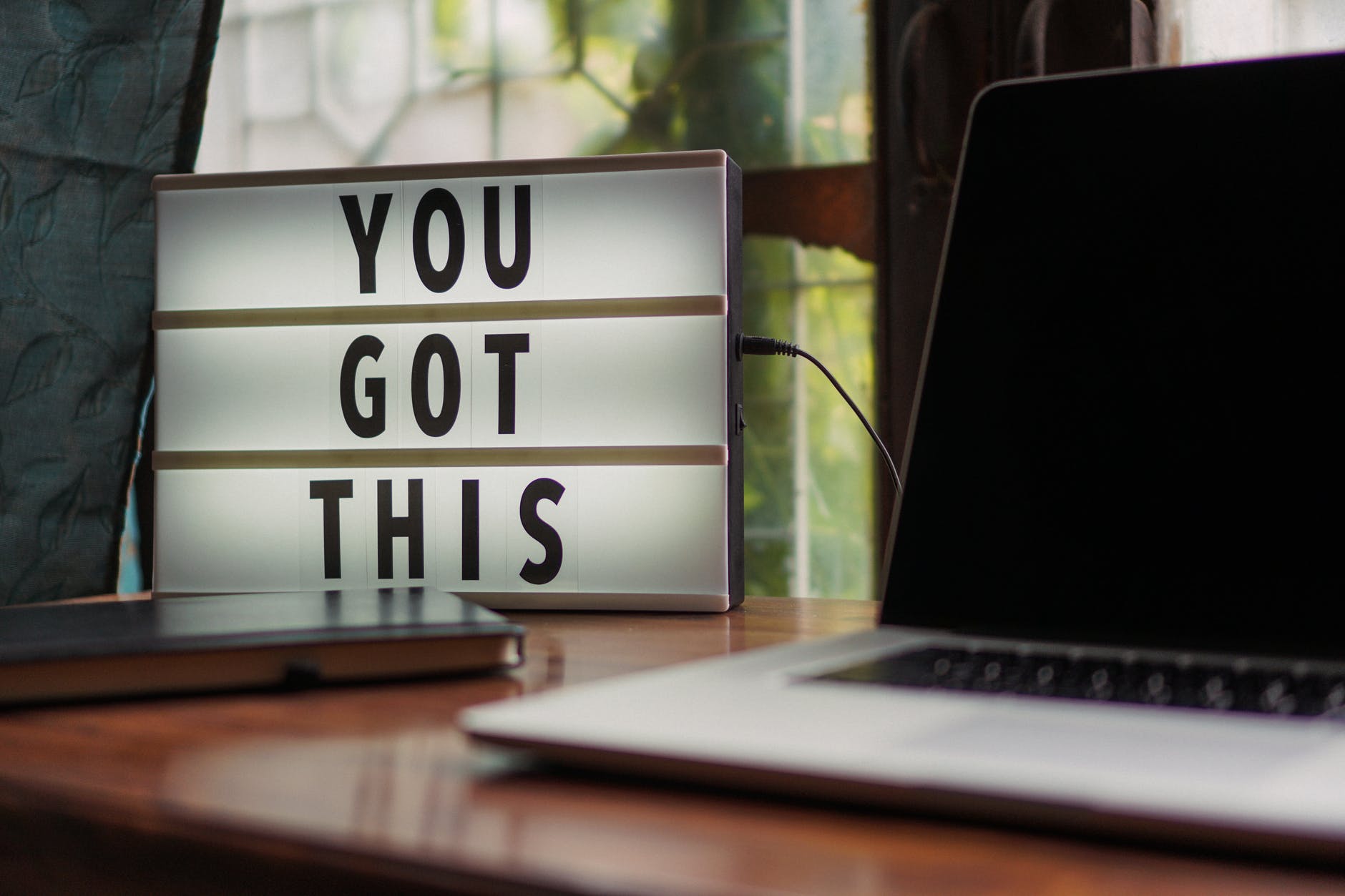 Image is of an open laptop with a lightbox next to it that reads "you got this".