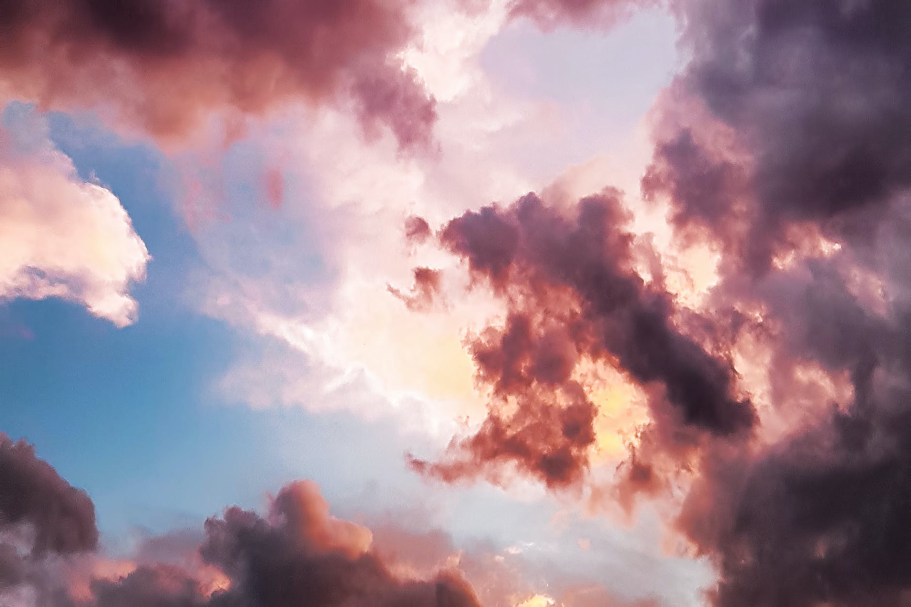 Image is of a blue sky, clouds and a sunset that has colored the clouds pink.