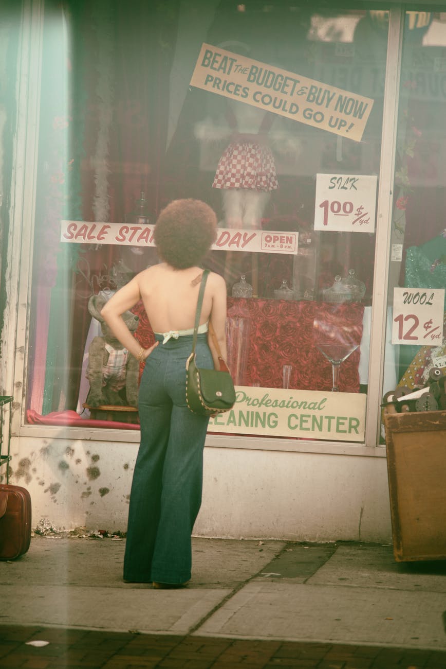Image of Black woman with an afro window shopping.
