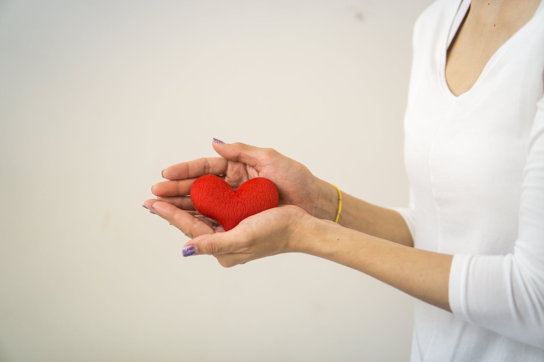 Image of a person holding a red heart in the palms of their hands.